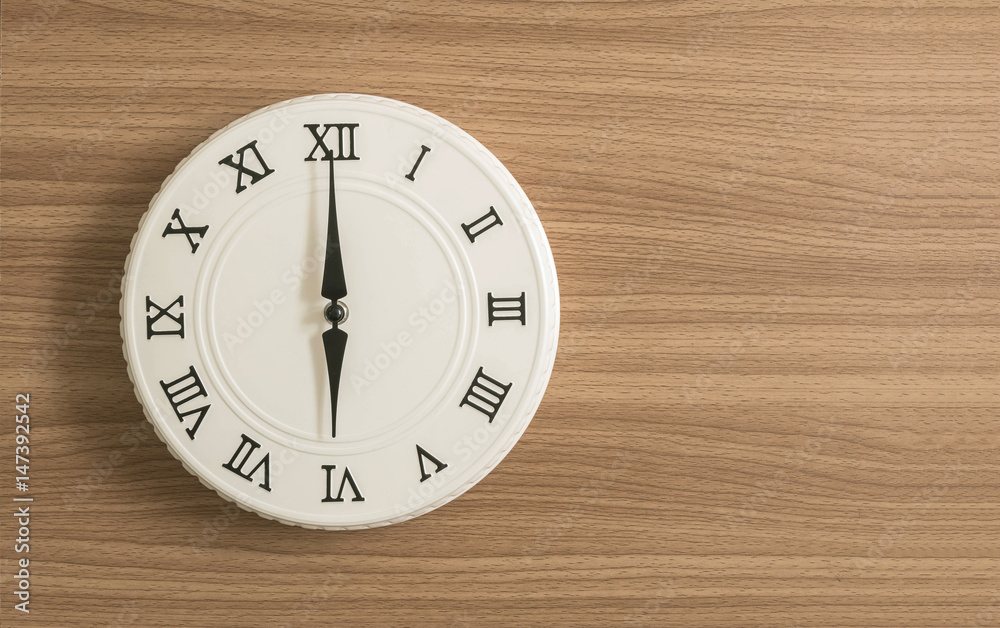 Closeup white clock for decorate in 6 o'clock on wood desk textured background with copy space Closeup white clock for decorate in 6 o'clock on wood desk textured background with copy space