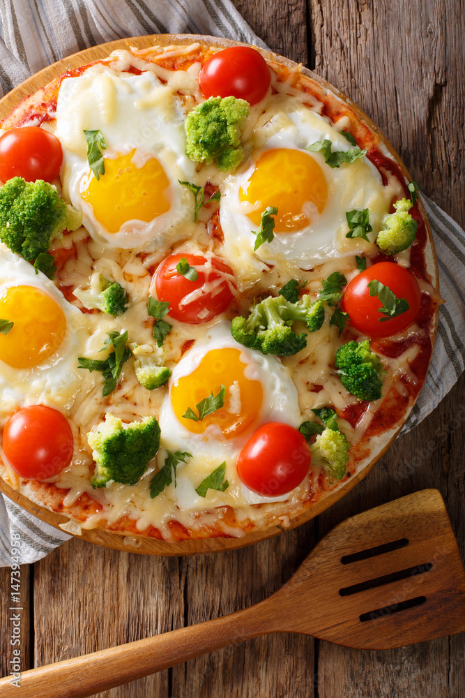 Pizza with eggs, cheese, broccoli, tomatoes and herbs close-up. Vertical top view Pizza with eggs, cheese, broccoli, tomatoes and herbs close-up. Vertical top view