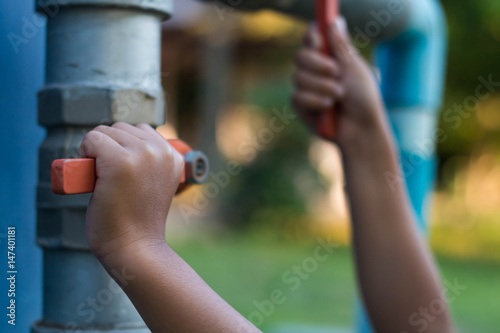 Children try to open the faucet close up.