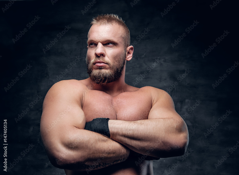 Studio portrait of brutal bearded muscular male over grey vignette background.