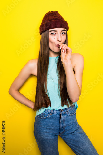 hipster girl bite lollipop on yellow background