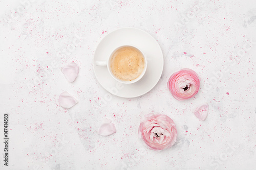 Beautiful ranunculus flowers and cup of coffee on white table top view. Breakfast in pastel color. Flat lay style.