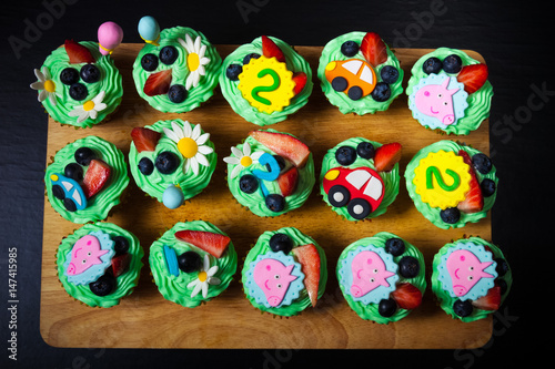 Set of homemade cupcakes with mastic decor for second birthday of child. Toned
