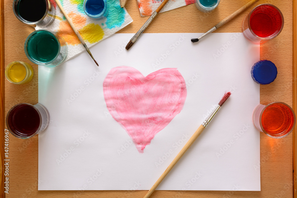 Watercolor heart on white paper among creative chaos on the table Watercolor heart on white paper among creative chaos on the table