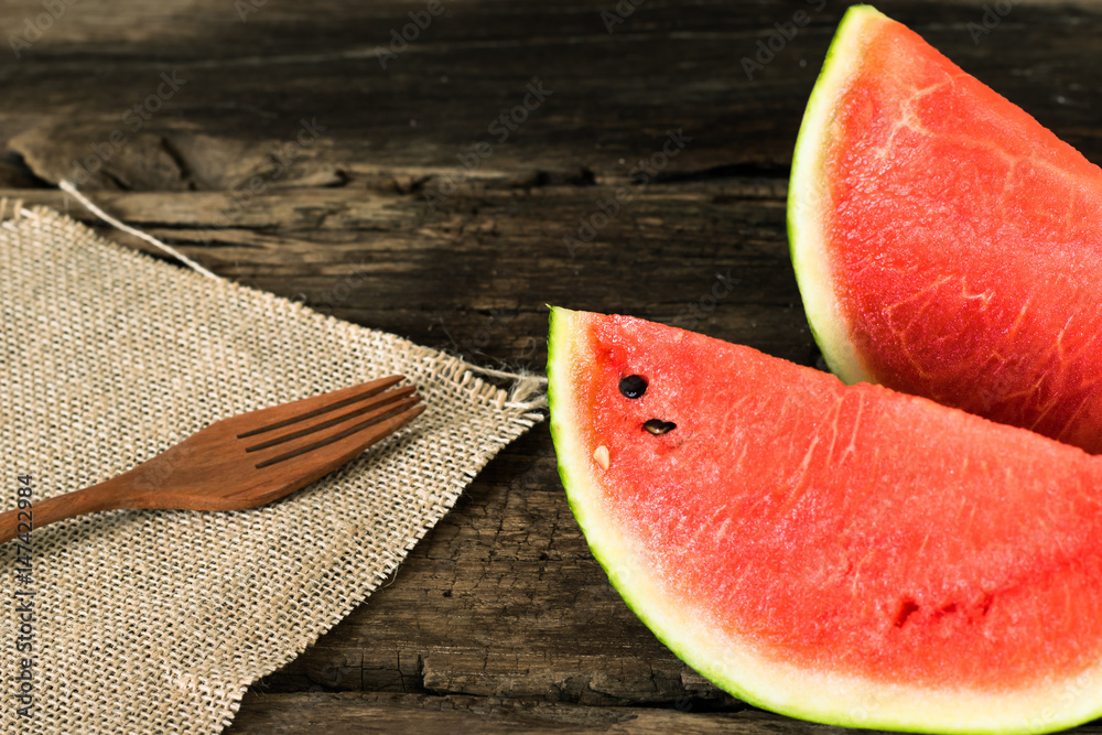 the watermelon on a rustic wooden table background with wood fork and sack cloth the watermelon on a rustic wooden table background with wood fork and sack cloth