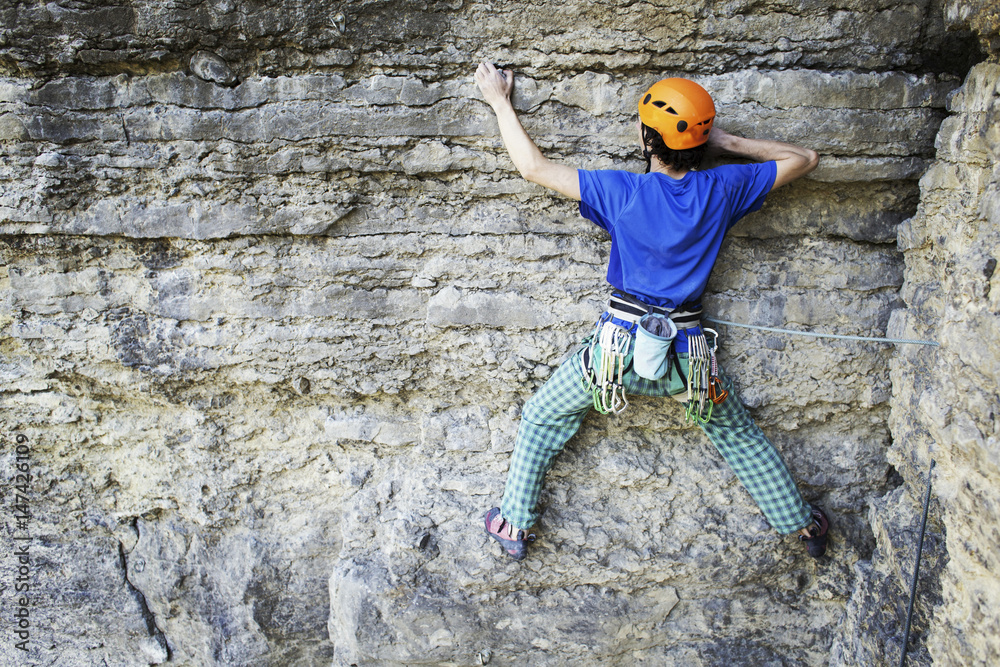 Fototapeta premium Rock climber reaching for his next hand hold, Joshua Tree National Park.