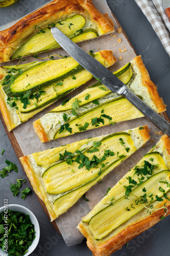 Tart with zucchini, ricotta cheese and parsley on a dark concrete background. Top view. Selective focus.