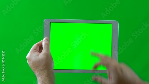 Man using tablet device against green screen.