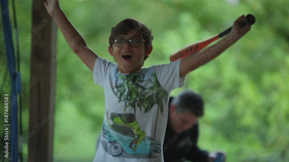 Cute kid practicing baseball in front of net with his father