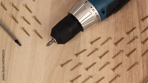 Carpenter screwing the crew with cordless screwdriver into wooden board