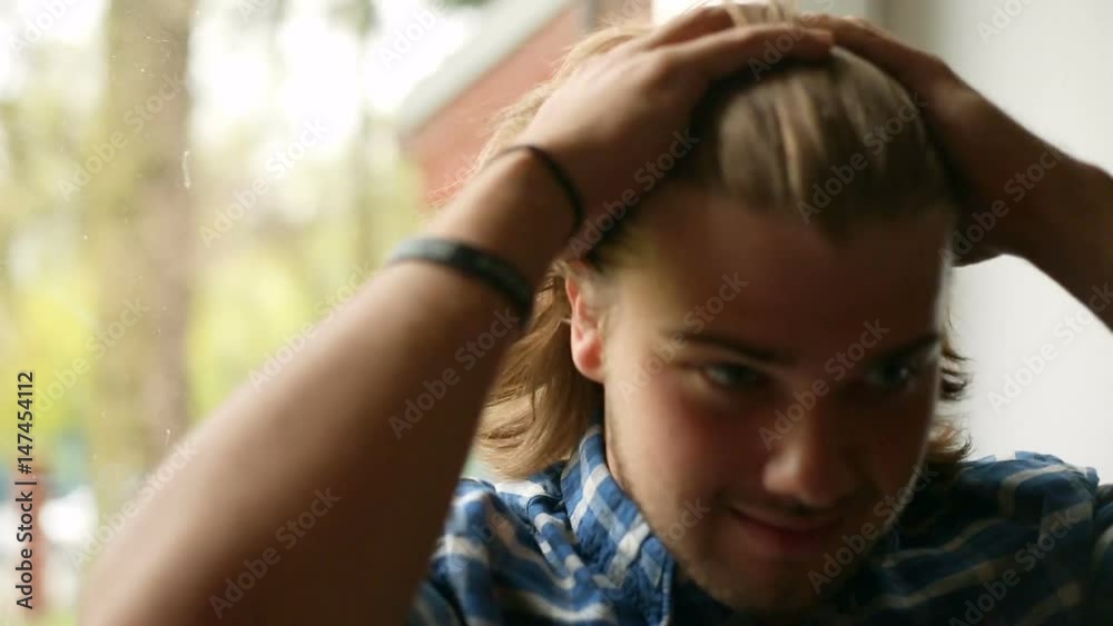 Handsome man touching his hair and smiling to the camera
