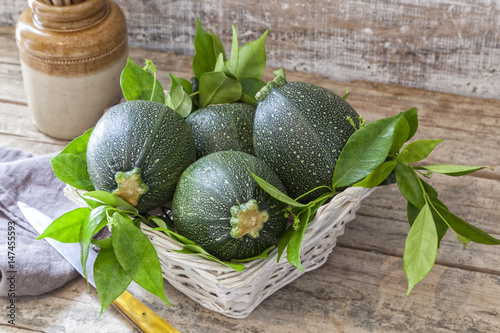 Round zucchini in a basket on a wooden table
