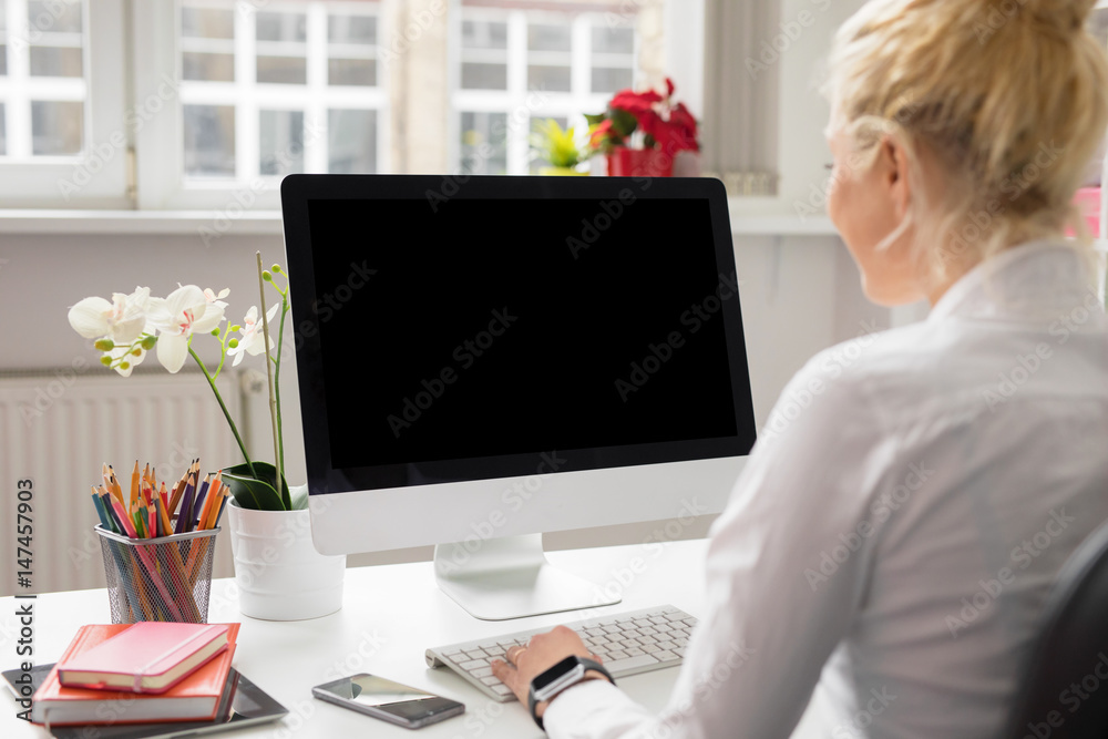Woman in office working on stationary computer - obrazy, fototapety, plakaty 