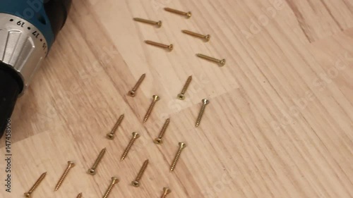 Carpenter screwing the crew with cordless screwdriver into wooden board