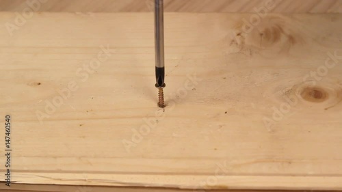 Hand of the worker screws in a wooden block with a screwdriver