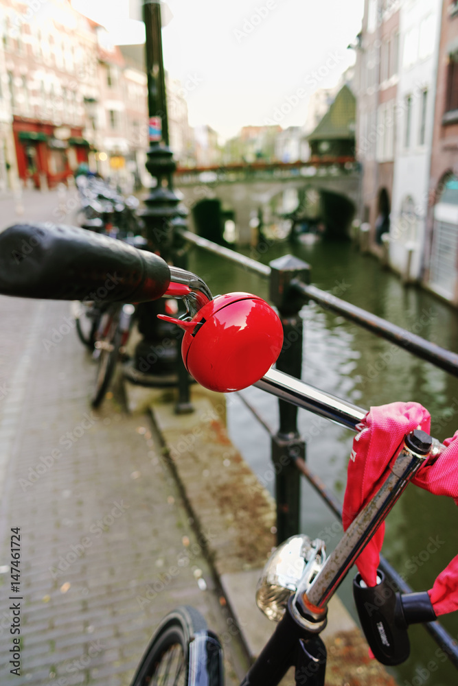 The bicycle with red bell stands near the city canal in Utrecht, cityscape, the Netherlands