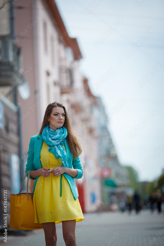Beautiful brunette young woman wearing nice dress, yellow handbag, walking on the street. Fashion city photo. Beautiful brunette young woman wearing nice dress, yellow handbag, walking on the street. Fashion city photo.