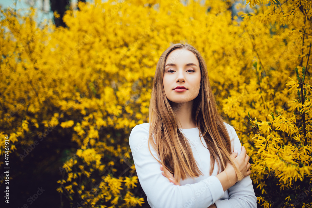Woman standing in front of yellow blooming tree in city street Woman standing in front of yellow blooming tree in city street
