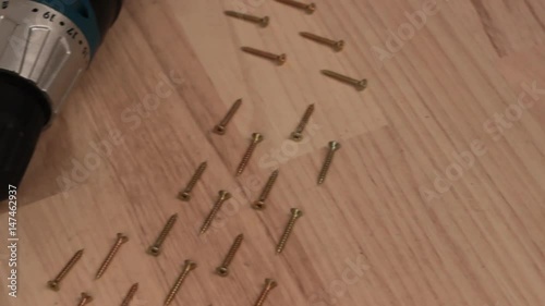Carpenter screwing the crew with cordless screwdriver into wooden board