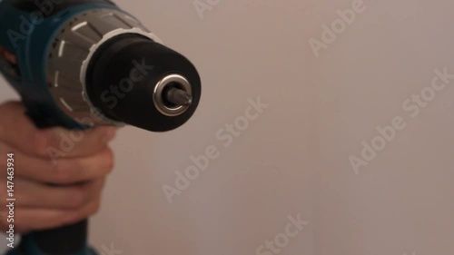 Electric screwdriver in hand at white desk background