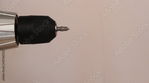 Electric screwdriver in hand at white desk background