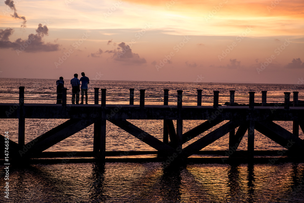 Obraz premium siluate picture 3 man walking on the bridge when sunset time