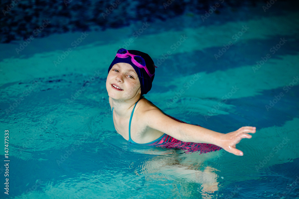 Little girl in pink googles swim in pool