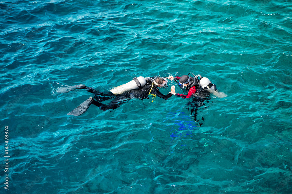 underwater, snorkeling divers in wetsuits swimming in sea