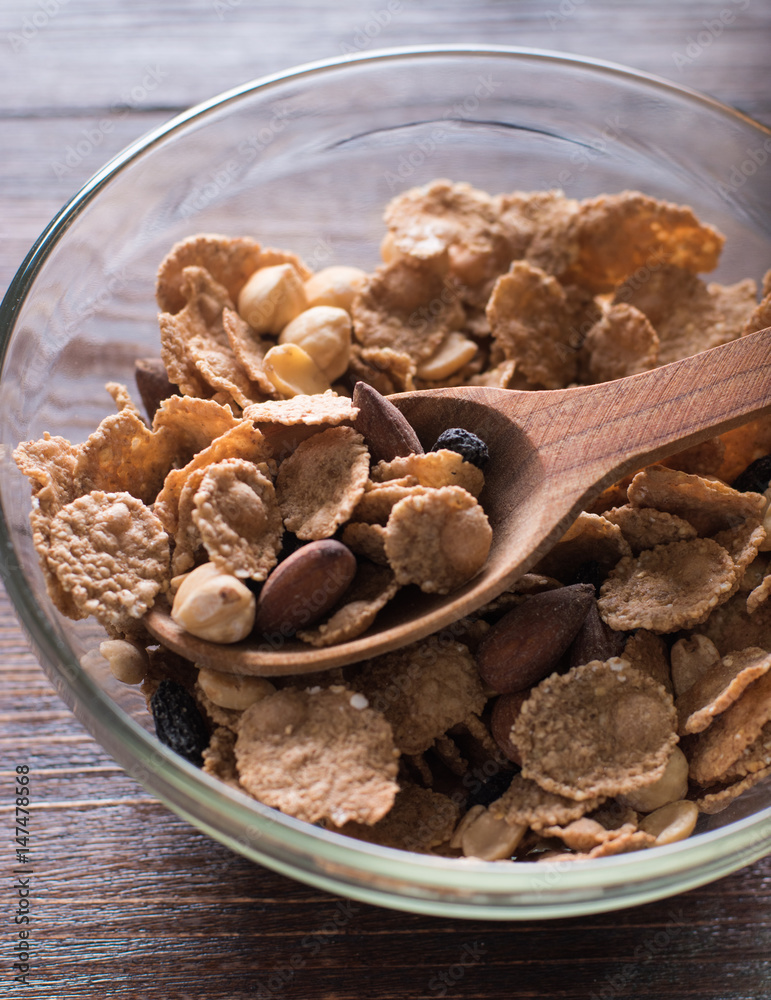 Obraz premium Oat flakes in bowl and wooden spoon with mix nuts, dry fruits on wooden background