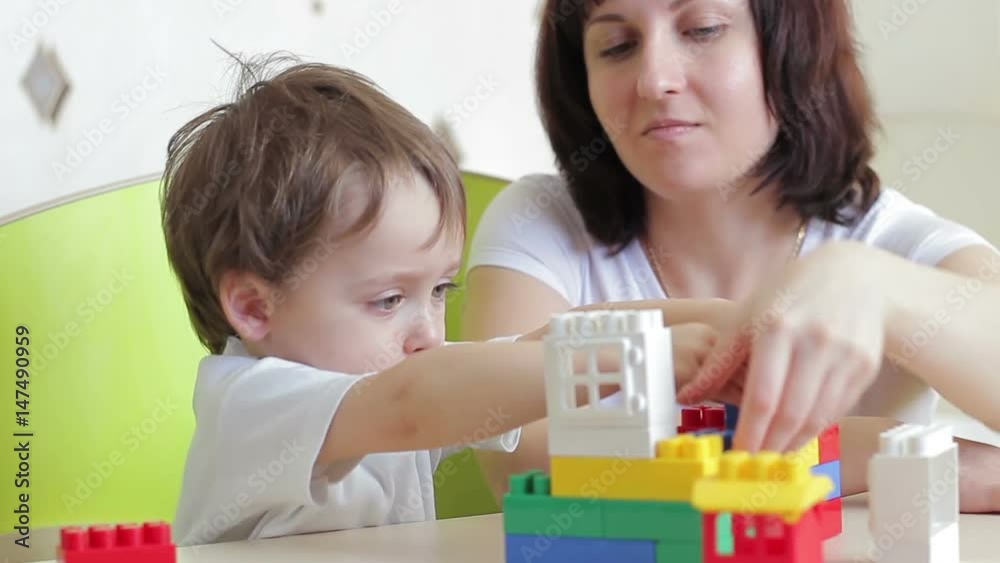 Mother and her child are playing with colored blocks Mother and her child are playing with colored blocks
