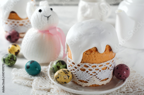 Traditional Orthodox Easter bread Kulich with colorful quail eggs on a light background. Selective focus.