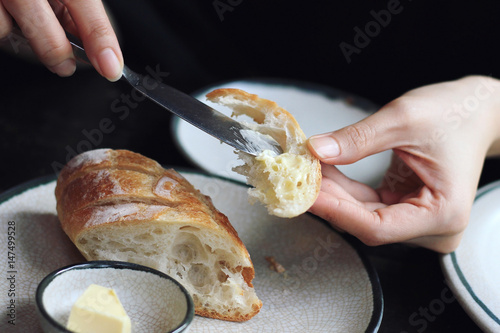 фотографія Close up of hands and  knife applying and spreading butter to bread