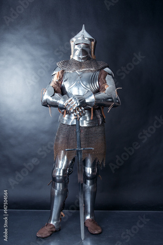 A medieval warrior in a helmet and with a sword. Knight on dark background