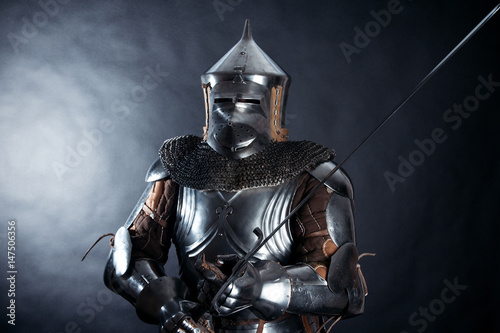 A medieval warrior in a helmet and with a sword. Knight on dark background