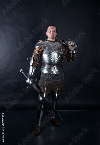 A medieval warrior with a sword. Knight on dark background
