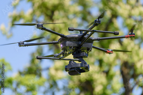 Fototapeta Naklejka Na Ścianę i Meble -  uav drone copter flying with digital camera in front of a tree