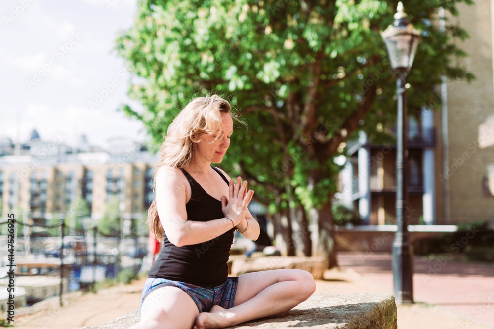 Woman in yoga praying position in front of harbour Woman in yoga praying position in front of harbour