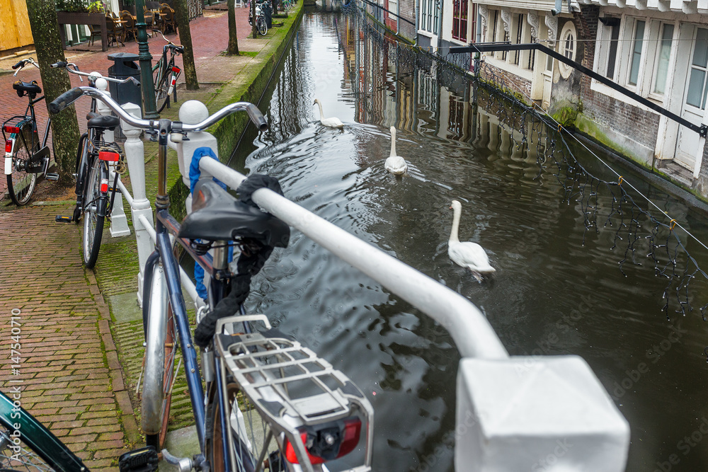 Canal with tunnel and historic street with bicycle parking lot in Dutch Delft old city