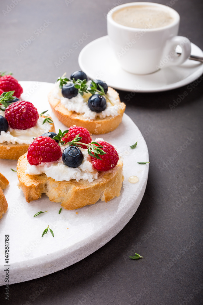Cup of coffee with berry and goat cheese sandwiches on marble cutting board, top view, copy space. Cup of coffee with berry and goat cheese sandwiches on marble cutting board, top view, copy space.