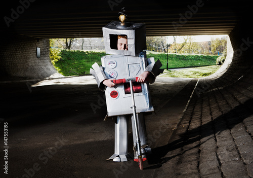 Boy dressed as robot riding scooter photo