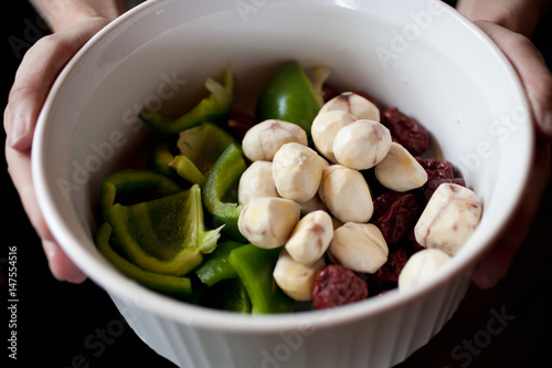 Person holding bowl of fresh cooking ingredients photo