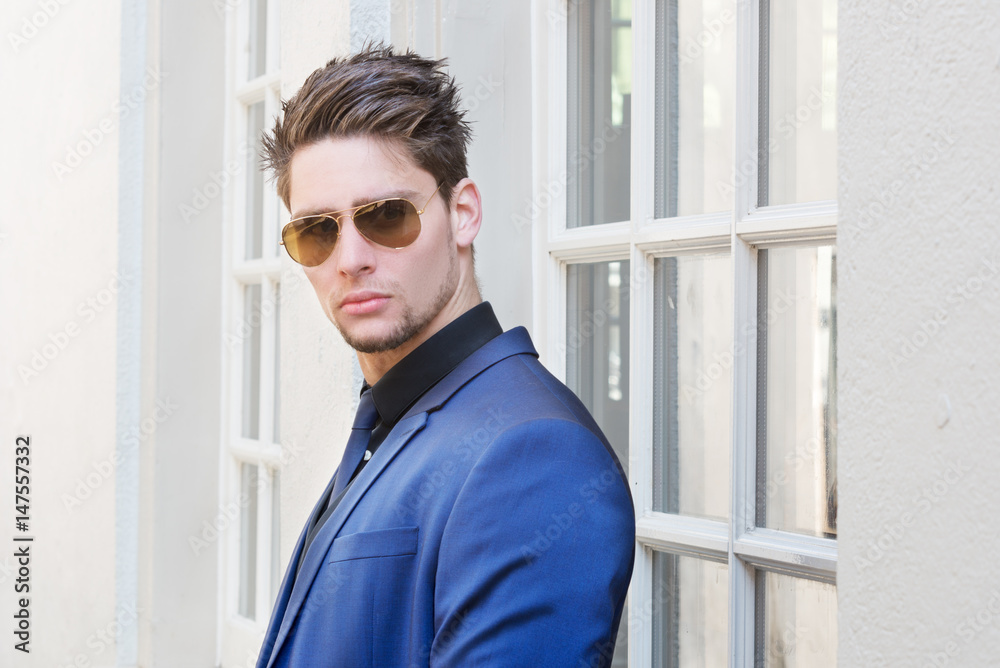 Handsome young man with short hair wearing classic blue suit and tie. Classic style. Outdoor shot