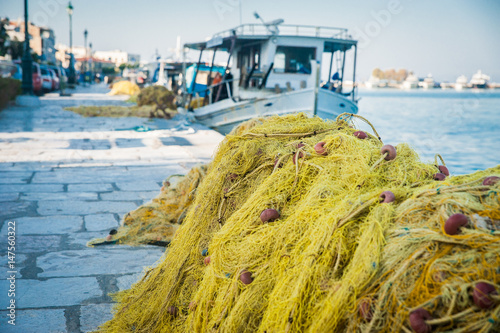 Obraz na płótnie Folded fishing nets on the coast with white boat in background, Greece w salonie