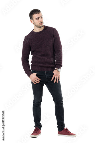 Serious confident macho casual man wearing maroon sweater looking away. Full body length portrait isolated over white studio background.