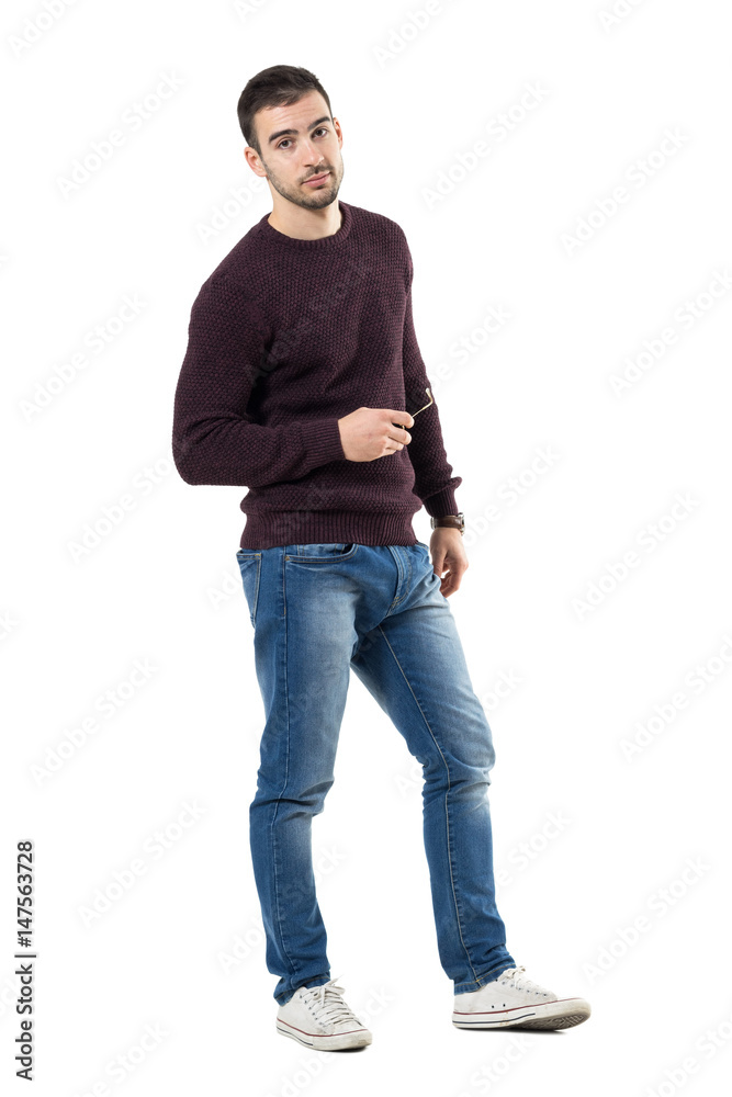 Relaxed young handsome casual man holding sunglasses looking at camera. Full body length portrait isolated over white studio background. Relaxed young handsome casual man holding sunglasses looking at camera. Full body length portrait isolated over white studio background.