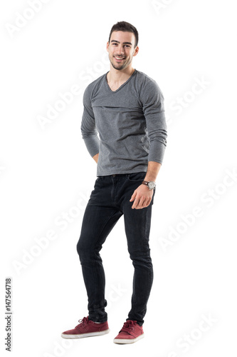 Cool young relaxed man laughing and looking at camera. Full body length portrait isolated over white studio background.