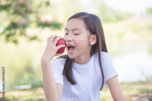Young asian girl eating apple in park
