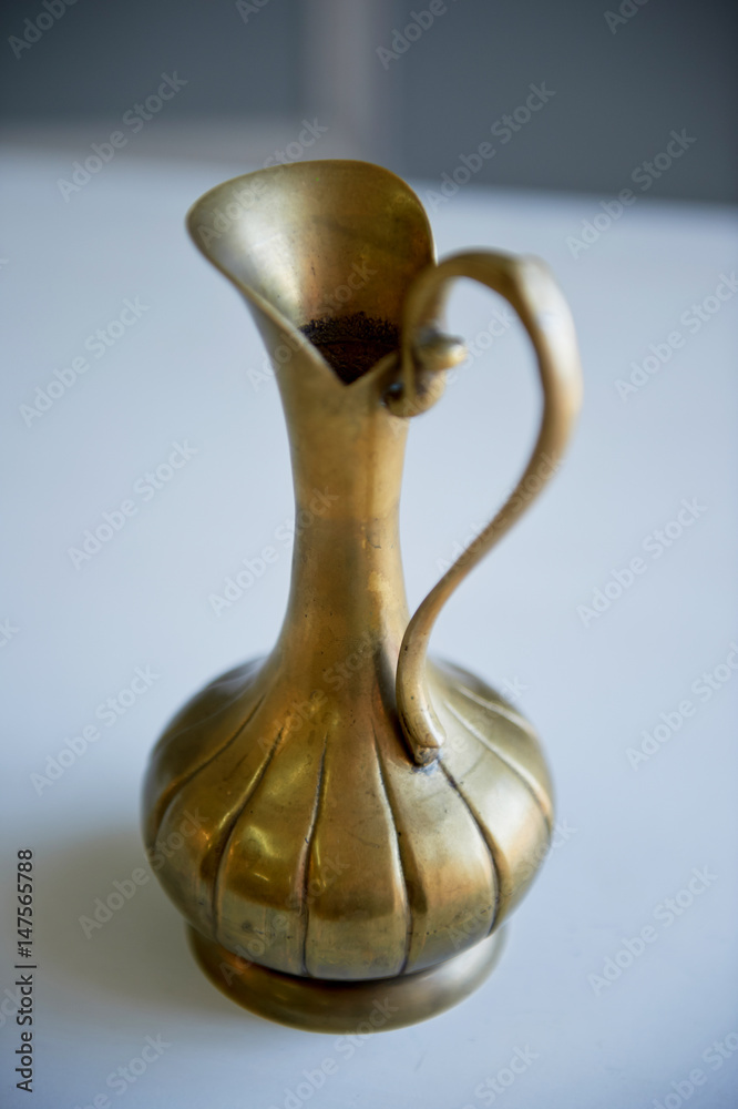 Old bronze pitcher on a light background.Retro Oriental style Old bronze pitcher on a light background.Retro Oriental style