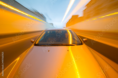 Front view of black car driving on high speed on a city at day time.