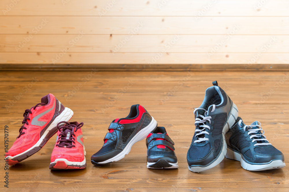 Three pairs of sports sneakers on a wooden floor close-up Three pairs of sports sneakers on a wooden floor close-up